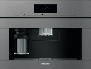 Built-in Miele coffee machine with a glass carafe on the left and a stainless espresso spout in the center.