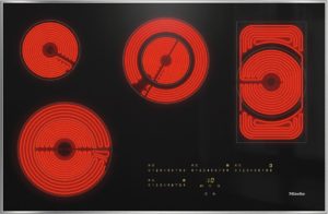 Electric coil stovetop with four glowing red burners on a black glass surface (Miele).