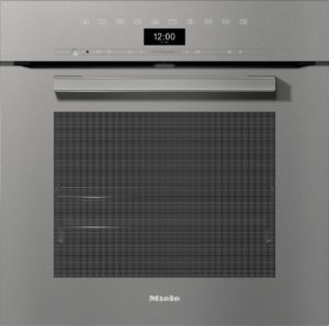 Front view of a Miele built-in oven with a digital clock reading 12:00, metal handle, and a large mesh oven door