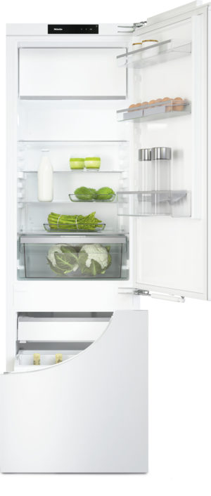 Open white refrigerator with organized shelves: milk, eggs, greens, and jars on the door shelves.