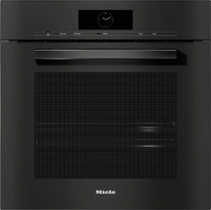 Front view of a black Miele built-in oven with a circular clock display, slim control panel, long handle, and a large textured door.
