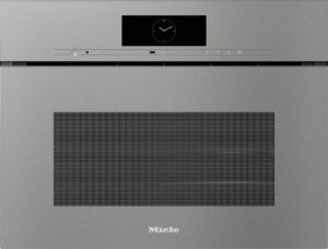 Front of a Miele built-in oven with a small circular clock display on a black panel and slim control strip above a wide vented door.
