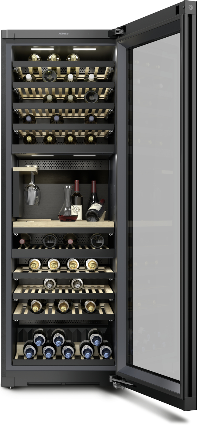 Tall wine refrigerator with an open glass door, showing multiple horizontal racks filled with wine bottles and a small storage area with decanters inside.
