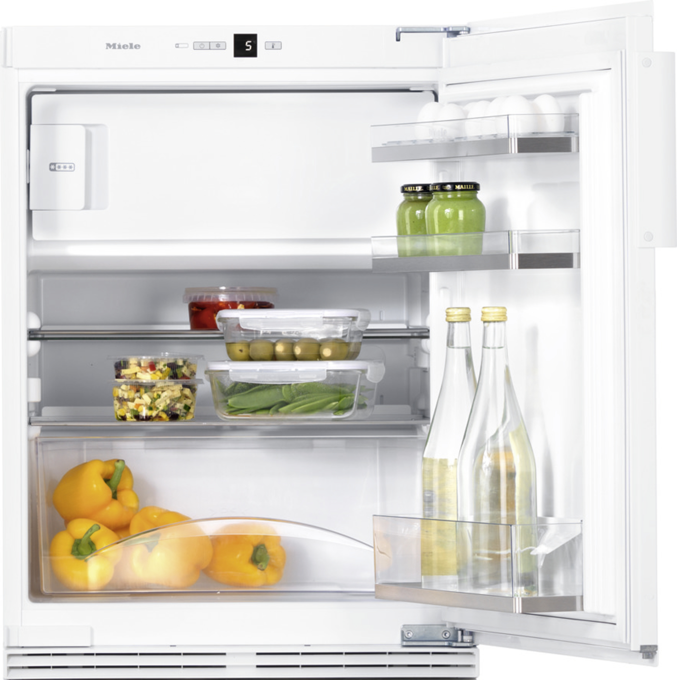 Open white refrigerator with shelves containing peppers, jars of olives, eggs, greens, and bottles on the door shelves.