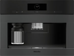 Miele built-in coffee machine with a black front, metal brew group center, and glass carafe on the left.