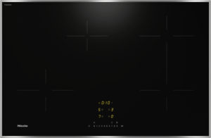 Black induction cooktop with a silver frame; centered digital control panel glowing yellow on a dark glass surface.