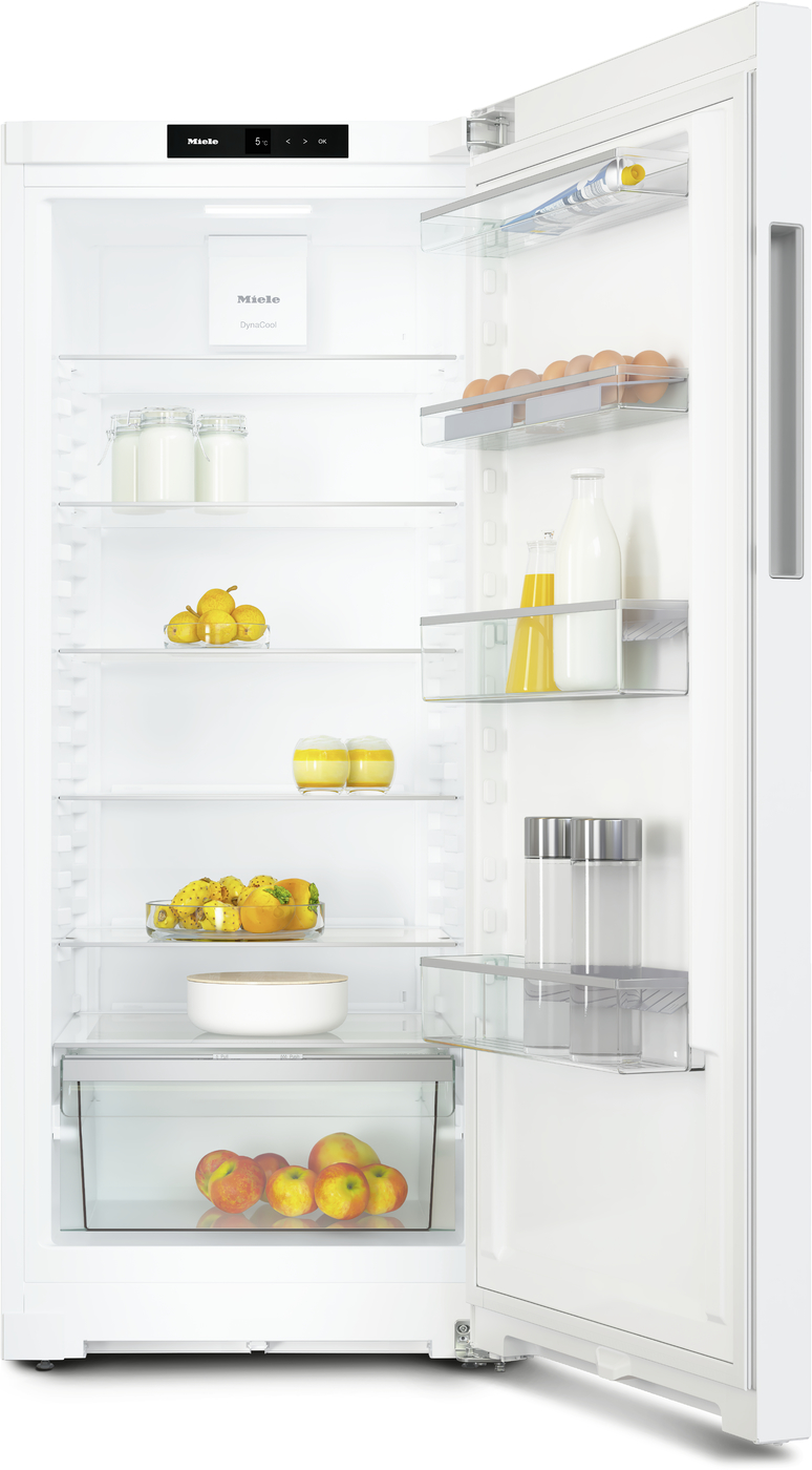 Open white refrigerator showing shelves with eggs, milk bottles, juice, and fruit including apples and oranges, plus a bottom fruit drawer