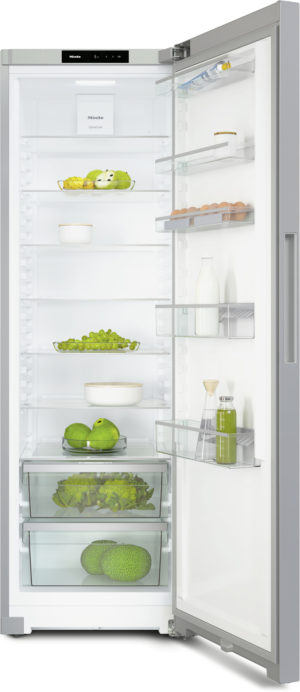 Open refrigerator showing organized shelves with dairy, eggs, greens, and bottles; clear glass drawers hold lettuce and vegetables.
