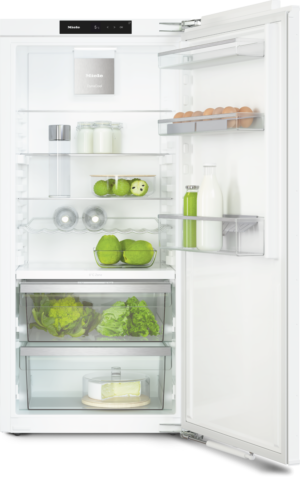 Open white fridge showing organized shelves: dairy, eggs, produce, and a cheese wheel on a glass drawer.