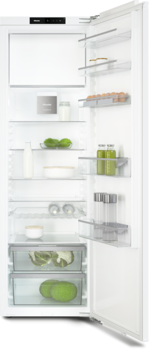 Open white refrigerator showing shelves with eggs, bottles, greens, and jars inside.