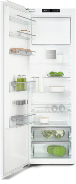 Open white refrigerator with eggs, milk, greens, and bottles on glass shelves; Miele branding visible on the top panel.