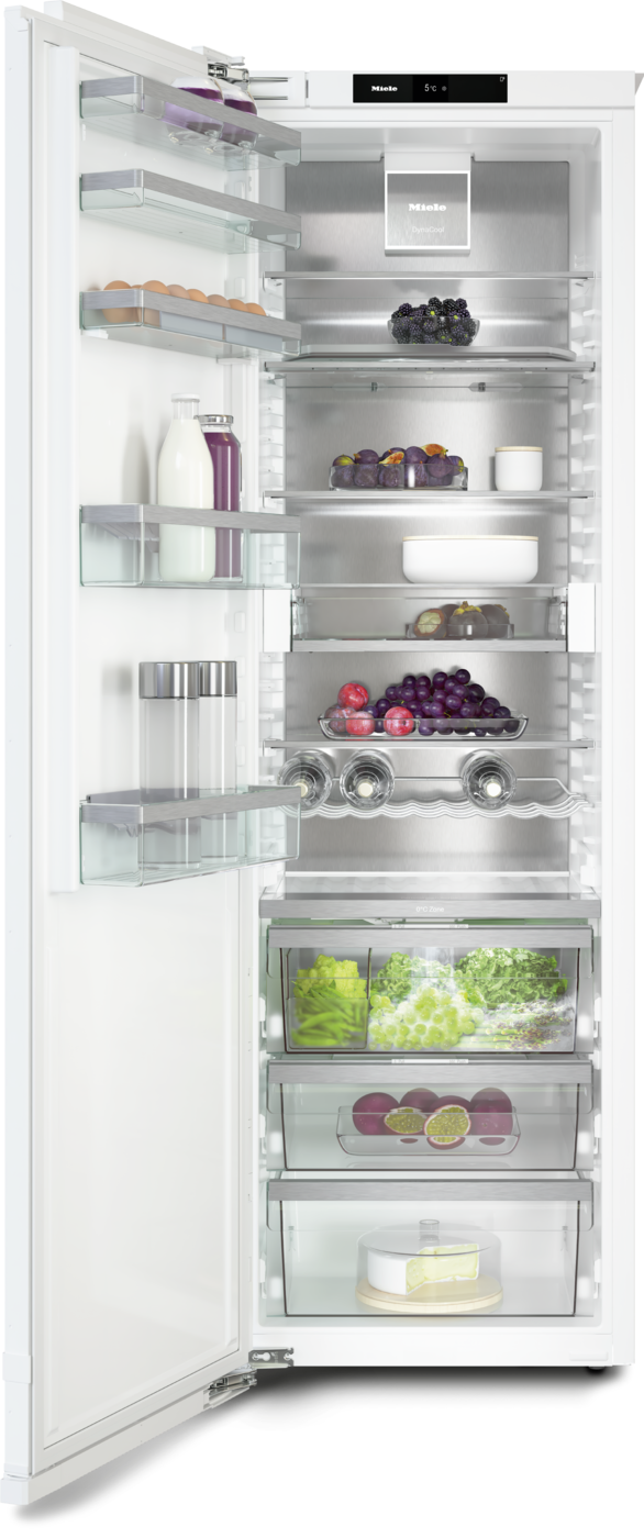 Open modern refrigerator filled with milk, juice, eggs, berries, grapes, lettuce, and a cake, organized on glass shelves and crispers.