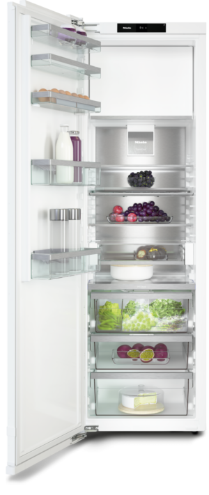 Open white refrigerator showing eggs, milk and juice, berries, grapes, greens, and a cheesecake on glass shelves and drawers.
