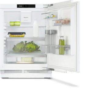 Open white refrigerator showing organized shelves with milk bottle, eggs, greens, and containers for condiments and juice, Miele branding visible.