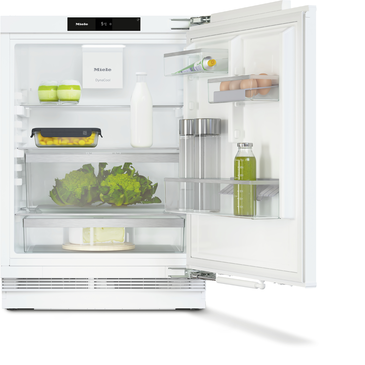 Open white refrigerator showing organized shelves with milk bottle, eggs, greens, and containers for condiments and juice, Miele branding visible.