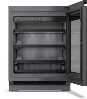 Miele reach-in commercial freezer with a glass door and empty adjustable shelves inside, lit interior.
