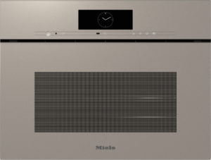 Beige Miele built-in oven front with a black clock display in the center and a slim control strip above a wide vented panel below the clock area.