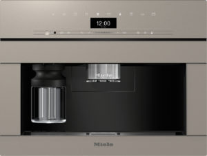 Built-in Miele coffee machine with a central espresso nozzle, digital display, and a glass carafe on the left.