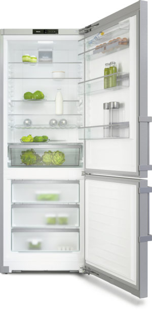 Tall side-by-side refrigerator with doors open, revealing organized shelves of milk, greens, eggs, jars, and vegetables plus a bottom freezer drawer.
