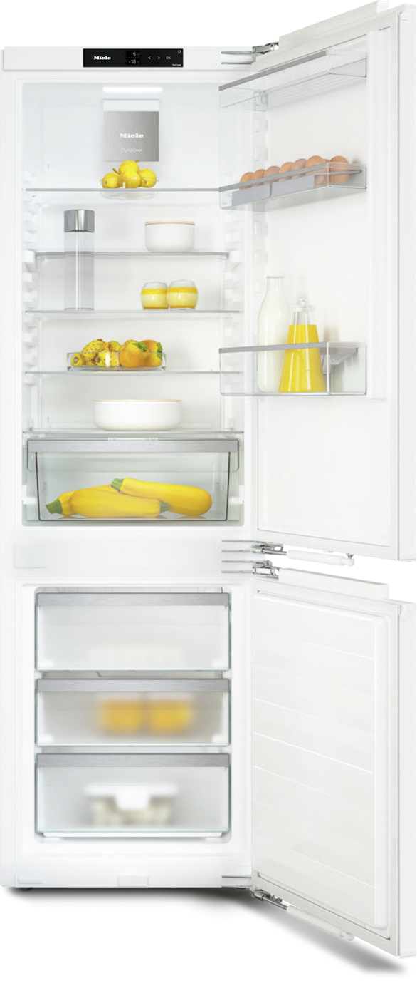 White refrigerator with the doors open, showing shelves stocked with lemons, bananas, eggs, milk, juice bottles, bowls, and a bottom drawer with squash.