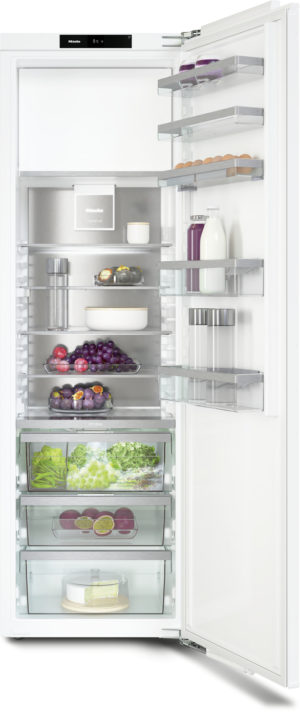 Open refrigerator with glass shelves containing eggs, dairy and juice bottles, fruits and greens, and a cake at the bottom.