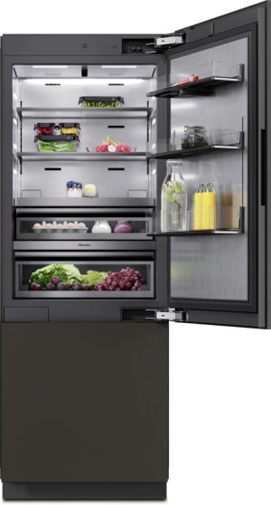 Open refrigerator showing shelves with vegetables, eggs, fruits, jars, and beverages; a bottom drawer holds greens and grapes.