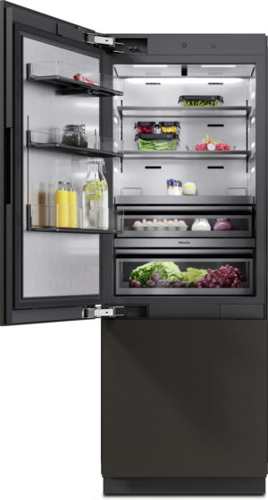 Open, black stainless refrigerator with multiple shelves and drawers, stocked with juice, water, lemons, veggies, eggs, and fruit inside.