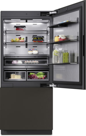 Open, built-in refrigerator with multiple shelves showing organized produce (fruits, vegetables), jars, eggs, and drinks; right door shelves display jars and bottles.