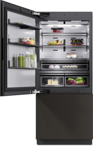 Open modern black refrigerator with LED lighting, showing shelves of fruits, vegetables, jars, bottles, dairy and eggs.