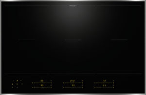 Miele induction cooktop with four cooking zones and a glowing yellow control panel at the bottom.