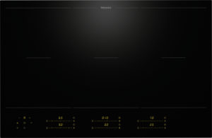 Miele black glass-ceramic induction cooktop with a slim control panel at the bottom showing yellow digital readouts.