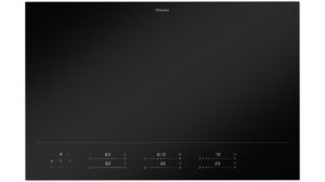 Miele black glass induction cooktop with a bottom touch-control panel and subtle indicator marks.