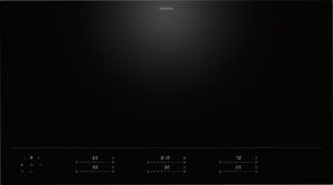 Black Miele induction cooktop viewed from above, with a sleek glass surface and a touch control panel along the bottom edge.