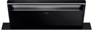 Black Miele range hood with chrome trim mounted over a flat island base, illuminated light bar visible under the hood.