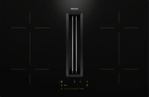 Sleek black Miele induction cooktop with a central vertical vent and slim control panel with yellow digital indicators at the bottom (high-contrast, minimal design).