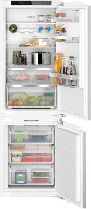 Open Siemens refrigerator with multiple shelves and a bottom freezer, showing bottles, jars, cheese, and vegetables organized inside and on the door.