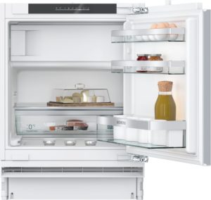Open white refrigerator interior with glass shelves, eggs in a tray, jars of condiments, and a tall bottle on the door shelf.