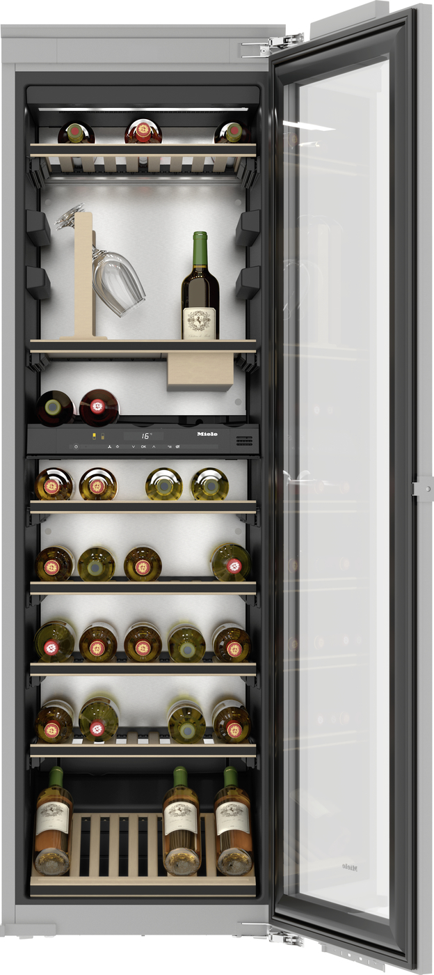 Interior of a tall wine fridge with the glass door open, showing multiple shelves loaded with wine bottles and a few glasses on a rack.