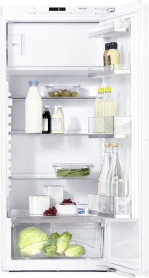 Open refrigerator with dairy, drinks, and vegetables on the shelves (milk bottle, yogurt, condiments, greens, cabbage).