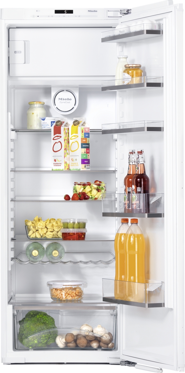 Open refrigerator with dairy, juice cartons, jars, fruit, and vegetables on shelves and door racks, showing organized storage around a white interior.