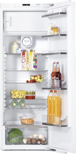 Open fridge with organized shelves: juice cartons, milk bottle, jars, fresh fruit and berries, drinks on the door, and a crisper with broccoli and mushrooms