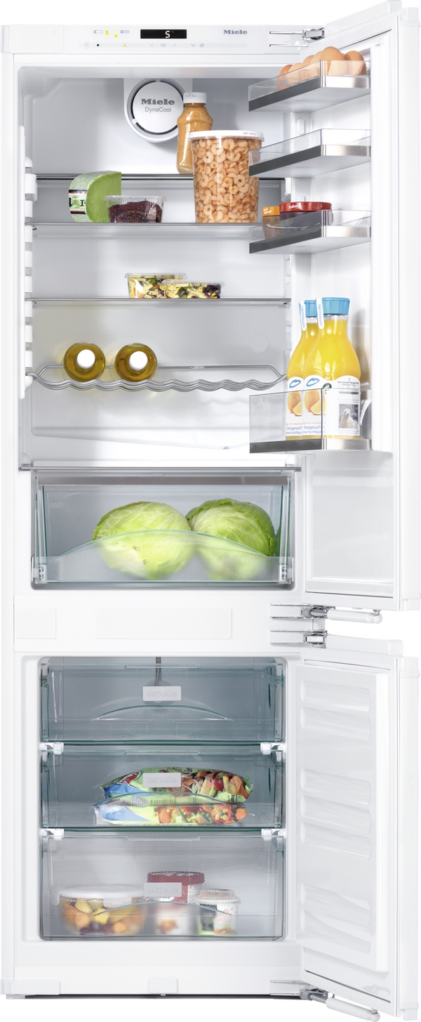 Open Miele fridge interior with eggs, orange juice bottle, jar of mixed vegetables, cheese wheel, and greens on glass shelves and door shelves in view.