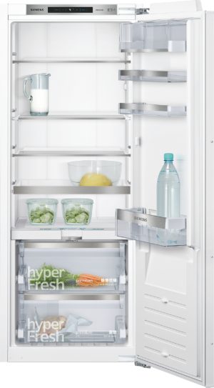 Open Siemens refrigerator interior showing milk jug on a shelf, a glass bowl with a lemon, and leafy greens in clear containers on lower shelves, plus a water bottle in the door.