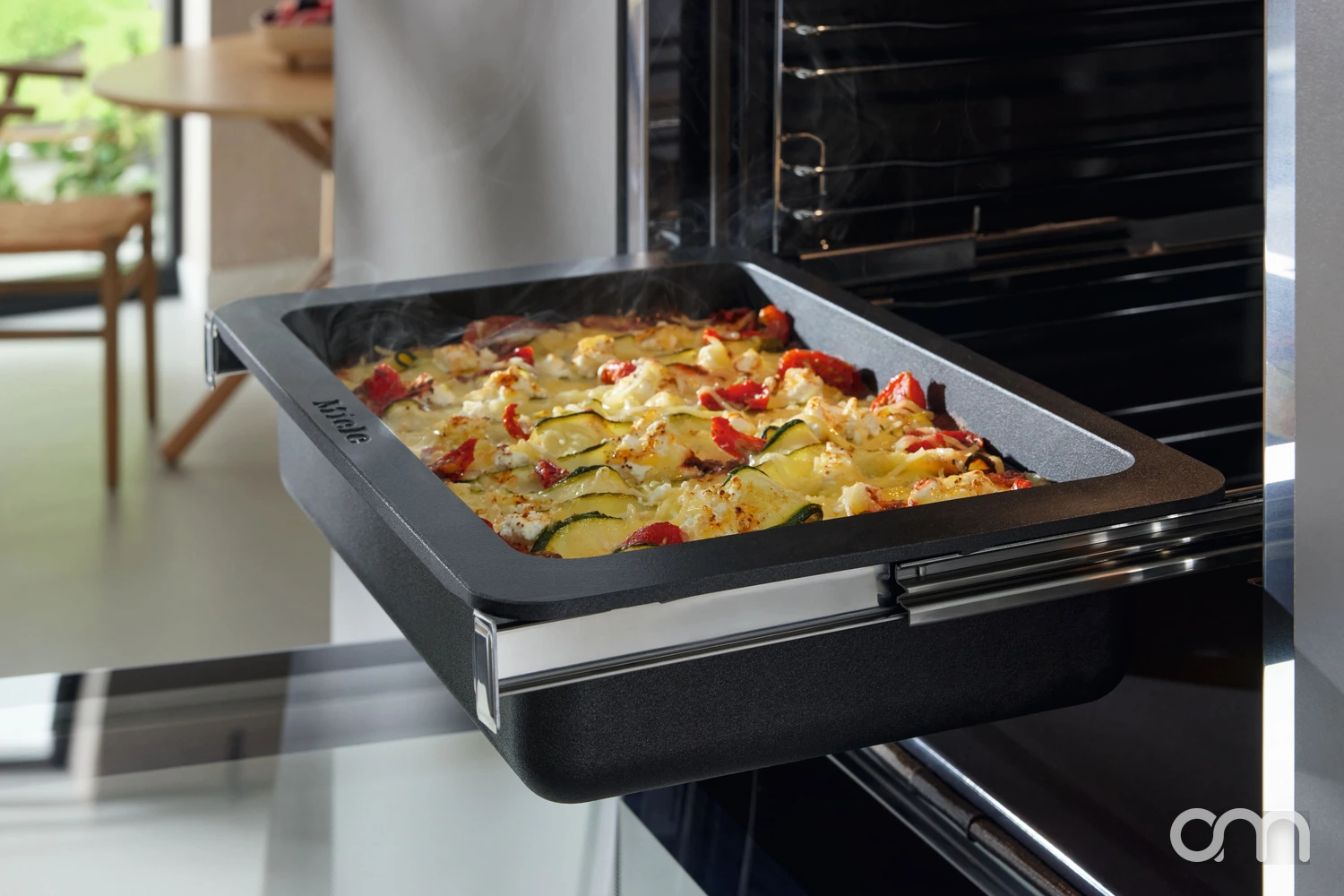 Plaque de cuisson Miele sortie d'un four encastrable sur rails télescopiques, gratin de légumes fumant