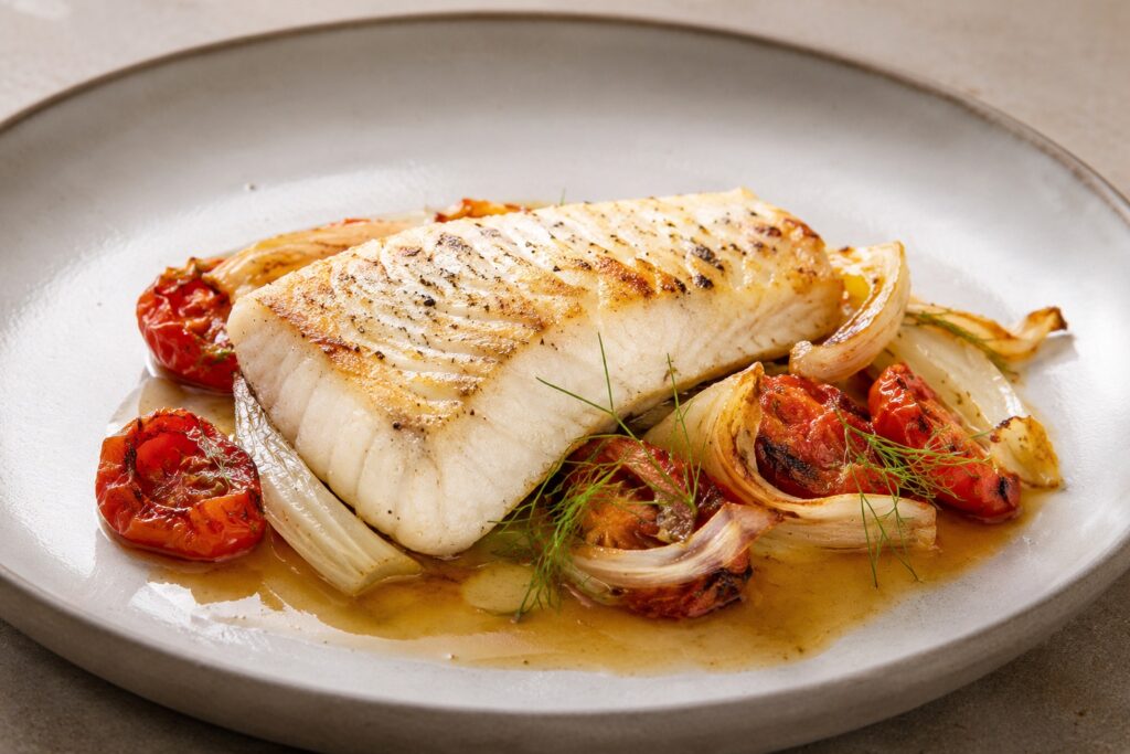 Filet de palée levé et servi à l'assiette avec fenouil, tomates confites et jus de cuisson