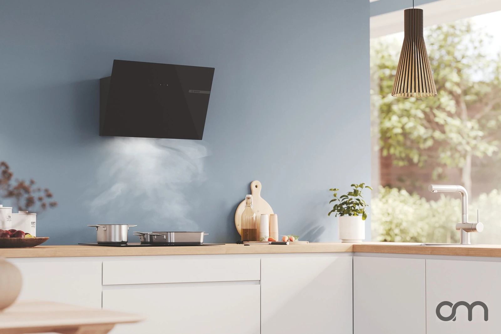 Hotte inclinée Bosch à façade en verre noir fixée sur un mur bleu gris au-dessus d'un plan de cuisson, vapeur aspirée : hottes Bosch conseillées et posées par Arts & Ménagers dans le canton de Neuchâtel