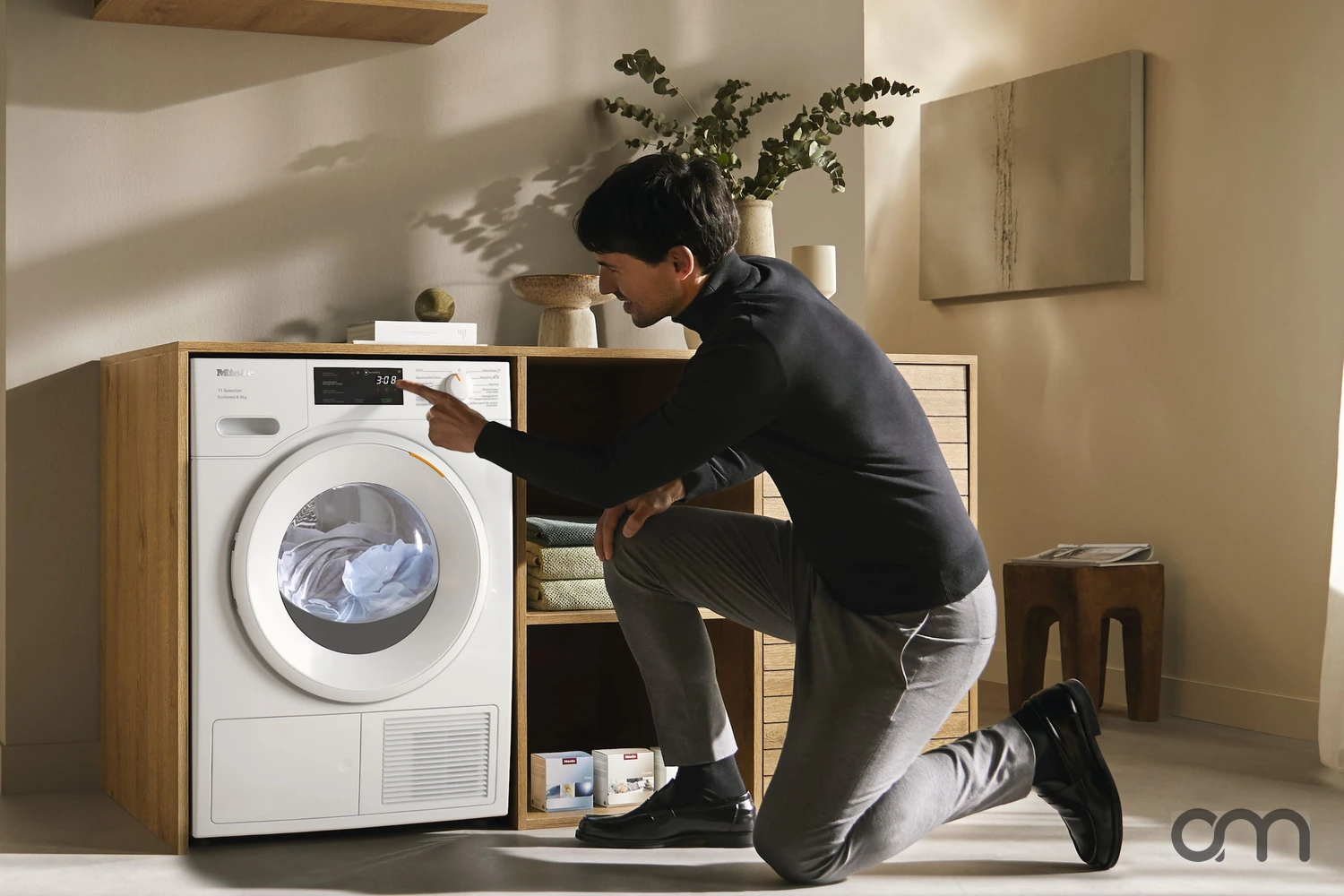 Entretien d'un sèche-linge à pompe à chaleur Miele, tambour ouvert avec du linge et réglage du programme, logement en Suisse romande