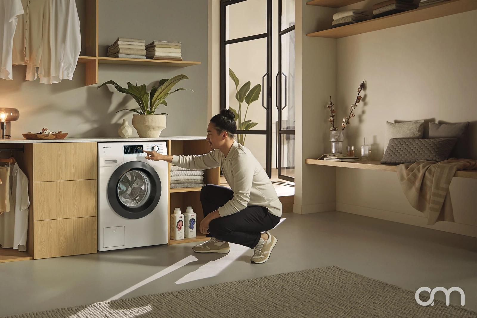 Homme lançant un programme délicat sur un lave-linge Miele dans une buanderie, lavage des vêtements d'hiver en Suisse romande